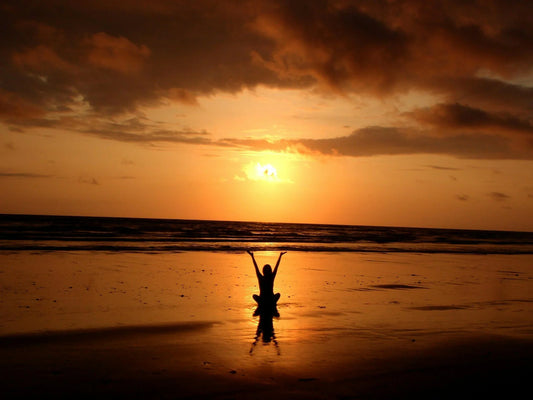 Person meditating at beach sunset-Benefits of Meditation