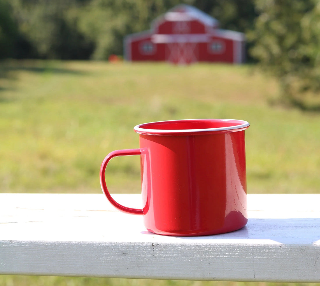 Red mug in front of a red barn