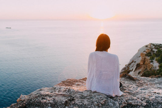 Woman sitting on rocks overlooking ocean