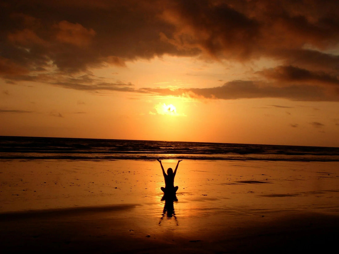 Person meditating at beach sunset-Benefits of Meditation