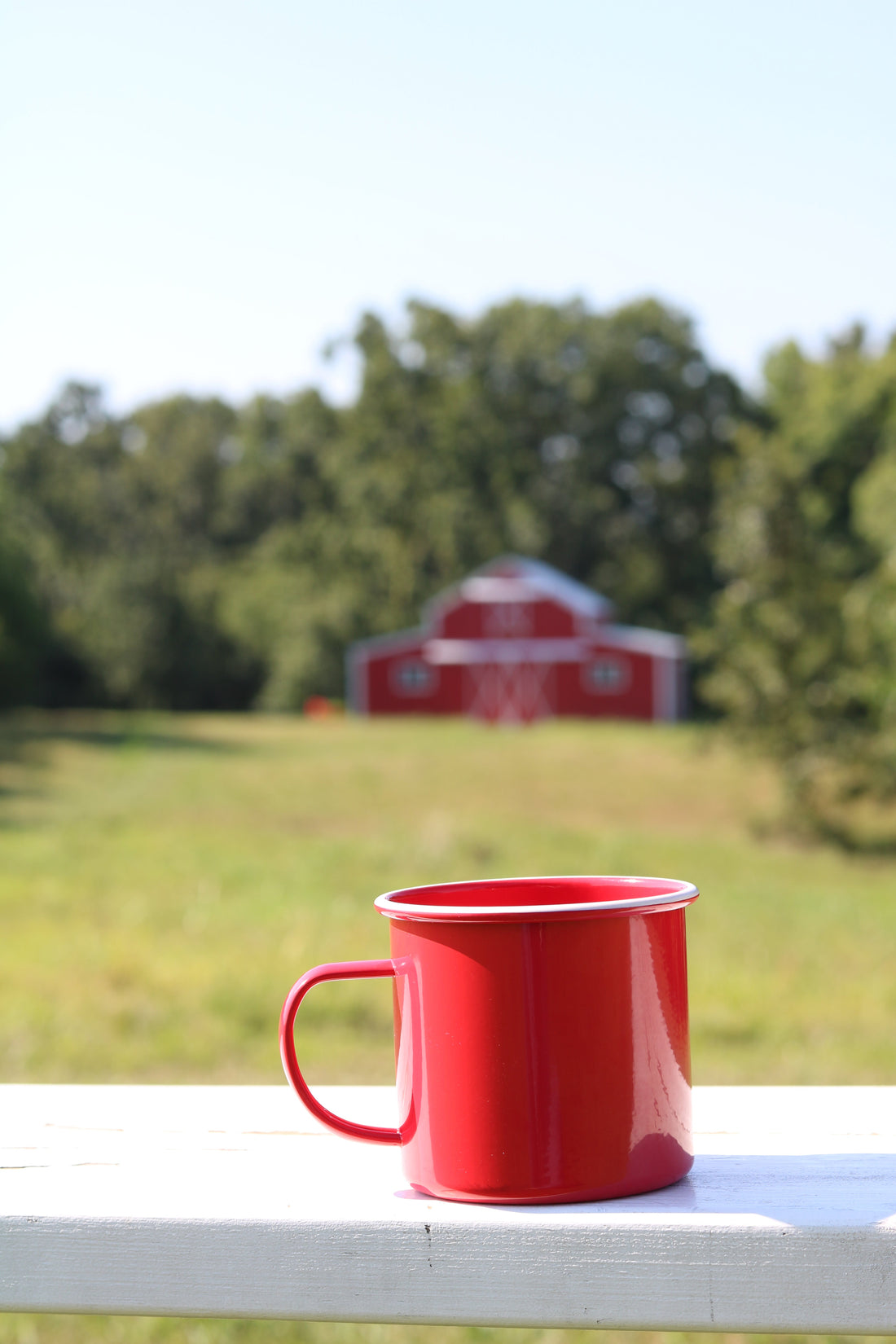 Red mug in front of a red barn