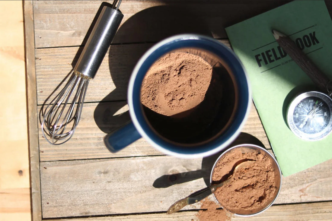 Mug of Daybreak Cacao with whisk and cacao powder