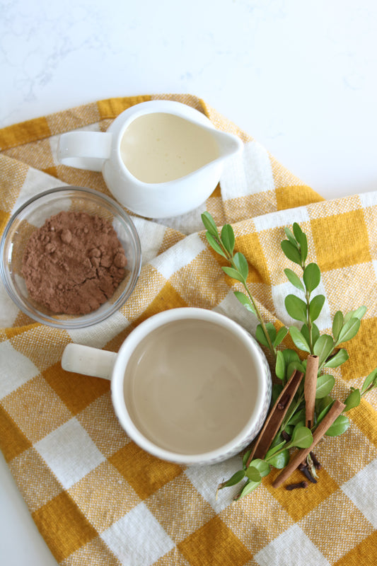Prebiotic-rich cacao powder on a table with a mug and cinnamon sticks